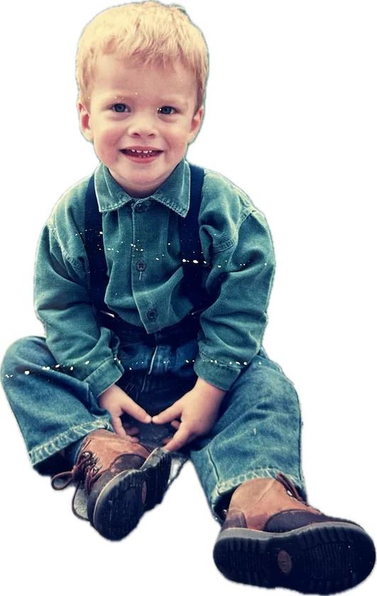 Bob as a little boy, sitting in denim and suspenders
